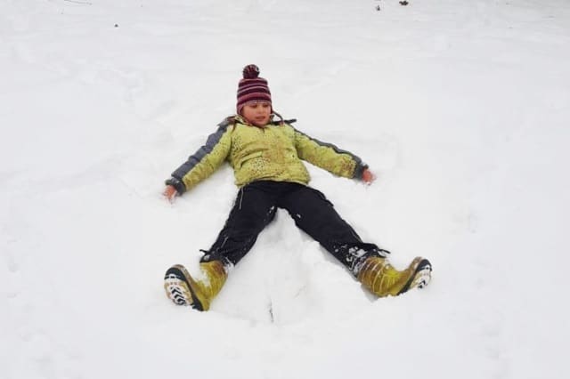 SchneengelWEB1 Kind erzeugt einen Schneeengel im frischen Schnee
